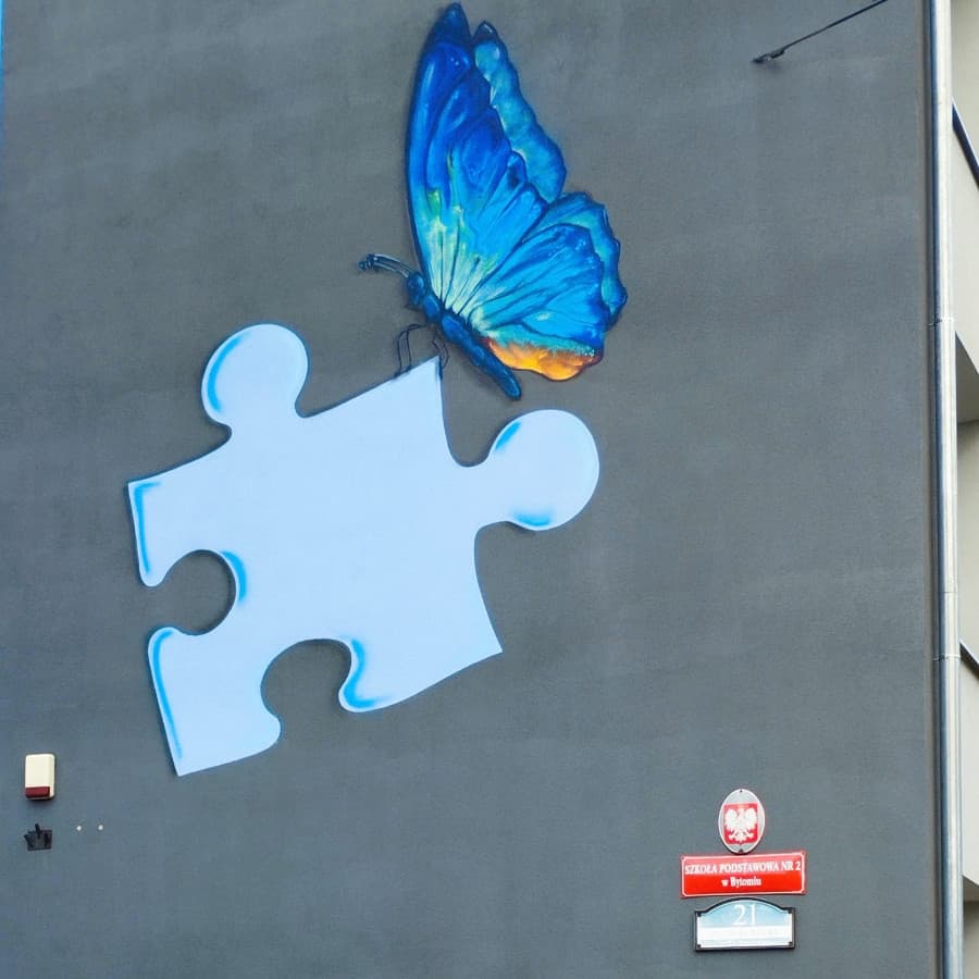 Mural z niebieskim motylem i puzzlem na elewacji Szkoły Podstawowej nr 2 w Bytomiu