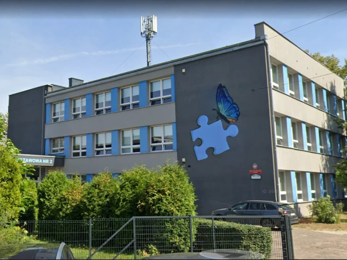 Namalowany na budynku szkoły specjalnej w Bytomiu niebieski motyl siedzący na niebieskim kawałku puzzle.