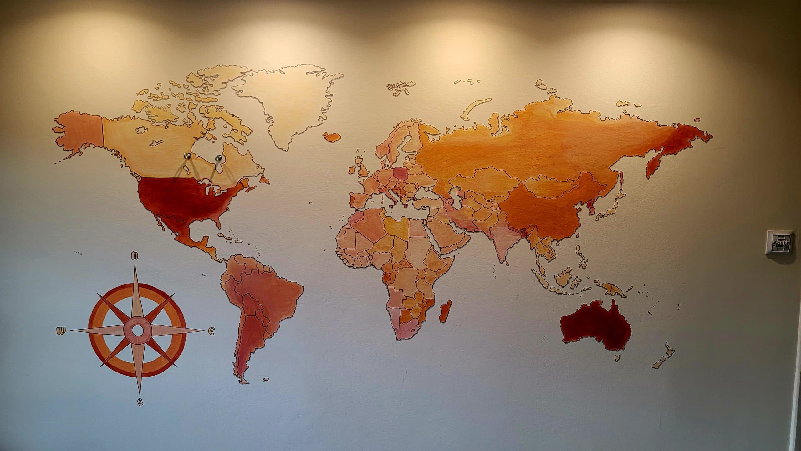 Ręcznie malowana mapa świata z różą wiatrów na ścianie salonu